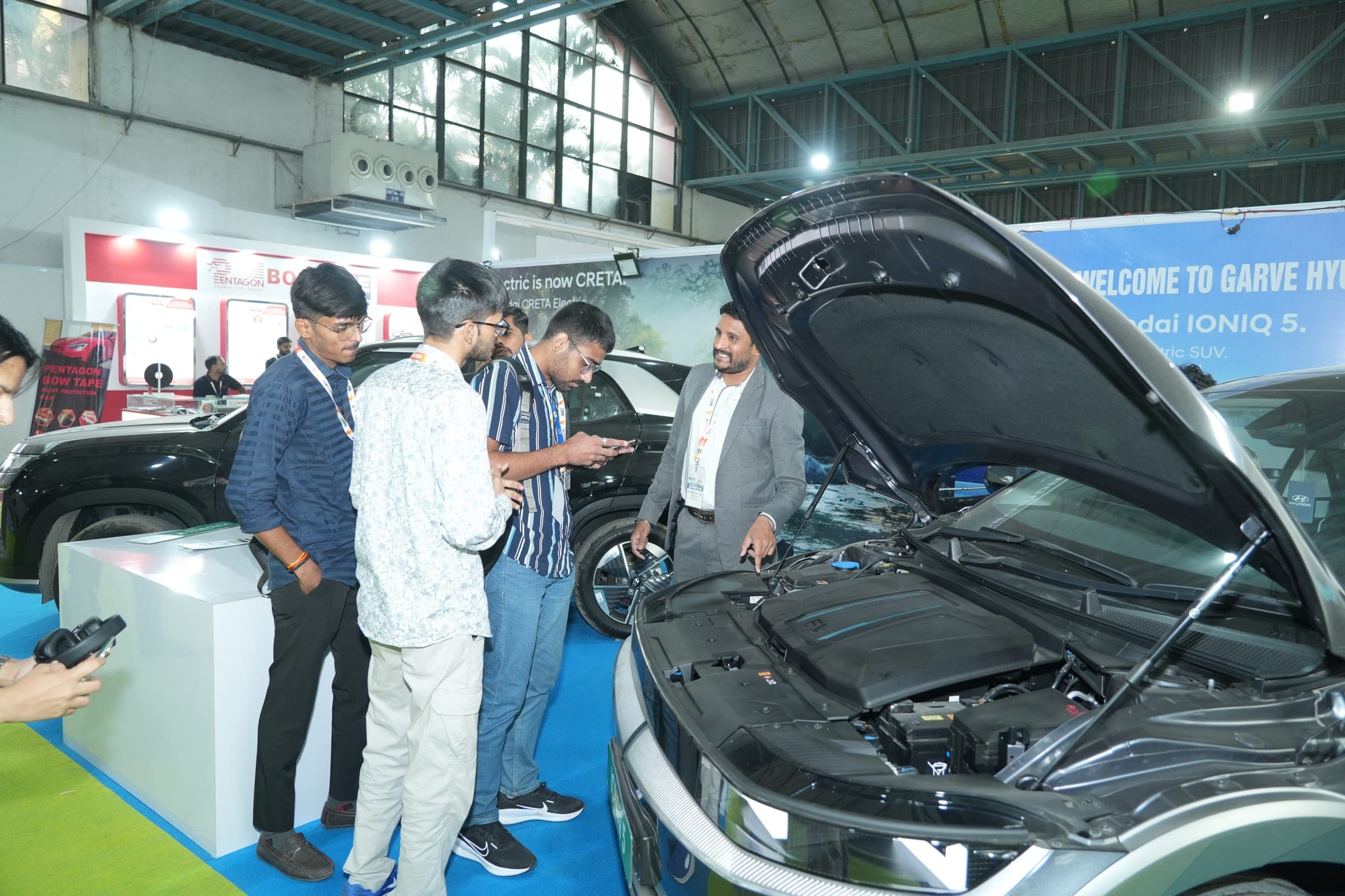 Visitors examining an electric vehicle's battery compartment at a previous Battery India Expo edition